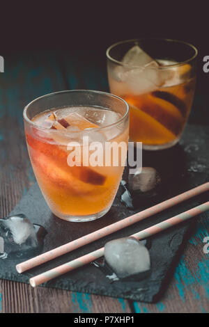 Peach aperol spritz avec tranches de pêches sur le bureau en bois. Cocktails d'été. Peach froid limonade. Banque D'Images