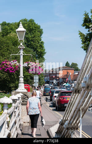 Femme marchant sur le pont suspendu au-dessus de la Tamise, vers la rue des boutiques, Marlow, Buckinghamshire, England, UK Banque D'Images