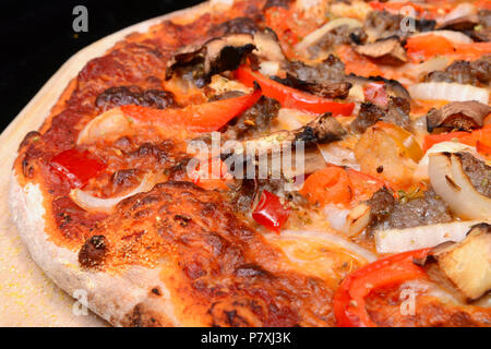 De délicieuses pizzas cuites au feu de bois four à pizza avec oignons, champignons, poivrons et de la saucisse Banque D'Images