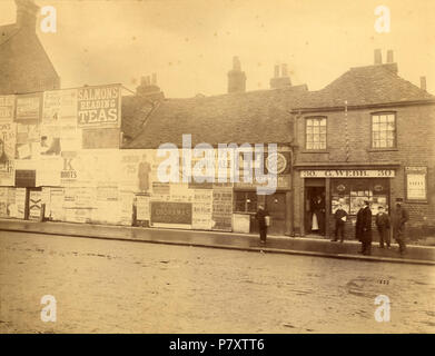 Anglais : Friar Street, Reading. Côté nord, ch. 1893. Nos 33 et 32 panneaux publicitaires publicité ont devant eux, appartenant à Hill et Sherwin, et bon nombre des annonces sont pour les magasins locaux. N° 31, la boutique de Thomas Hickman, concessionnaire de bottes et de chaussures, est visible, et à côté, à l'angle de la Place des marchands, n° 30, la boutique de George Webb, avec un poteau de barbier à l'extérieur. 1890-1899 : photo par Walton Adams. 1893 rue 164, lecture, côté nord, ch. 1893 Banque D'Images