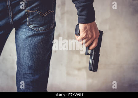 Close up of man holding hand gun. Homme portant un jean bleu. Voleur et terroristes concept. Soldat de la police et de concept. Thème d'armes nucléaires Banque D'Images