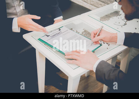 Deux hommes d'contact signature lorsque nouveau projet Accord de démarrage à l'intérieur. Entreprise et contact concept de signature. Soft et split à l'usinage transversal Banque D'Images