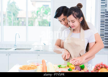 Les amoureux de la cuisine asiatique ou couple et découpage des légumes dans la cuisine chambre. L'homme et de la femme à l'autre dans la maison. Maison de vacances lune de miel et de concept. Valenti Banque D'Images