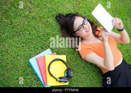 Femme portant sur l'herbe et à l'aide de la tablette, l'éducation, technologie concept concept Banque D'Images