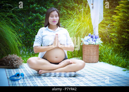 Pregnant woman doing yoga à l'extérieur. L'exercice et la méditation concept Banque D'Images