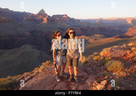 Deux jeunes femmes les randonneurs pour le coucher du soleil sur l'extrémité nord-ouest de Horseshoe Mesa dans le Parc National du Grand Canyon, Arizona, United States. Banque D'Images