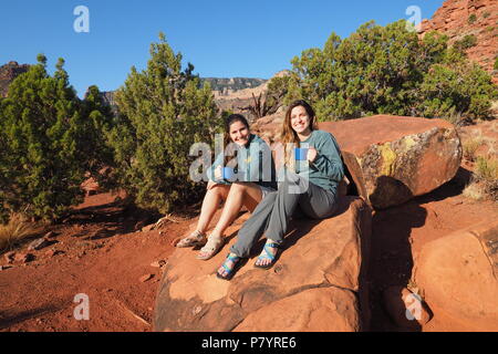 Deux jeunes femmes backpackers reposant sur un rocher sur Horseshoe Mesa dans le Parc National du Grand Canyon, Arizona, United States. Banque D'Images