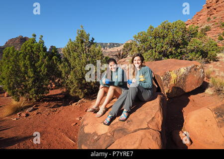 Deux jeunes femmes backpackers reposant sur un rocher sur Horseshoe Mesa dans le Parc National du Grand Canyon, Arizona, United States. Banque D'Images