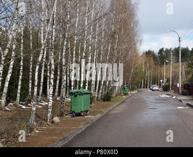 Conteneurs à ordures en plastique vert installés le long de la route dans un village européen moderne. Journée de printemps paysage rustique Banque D'Images