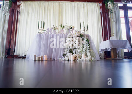 Guirlande de fleurs roses en forme de pin se bloque à partir de la table. Décoration de mariage, en art floral. Candélabres avec bougies verte.L'inscription M. et Mme. Enroulez la table avec chiffon Banque D'Images