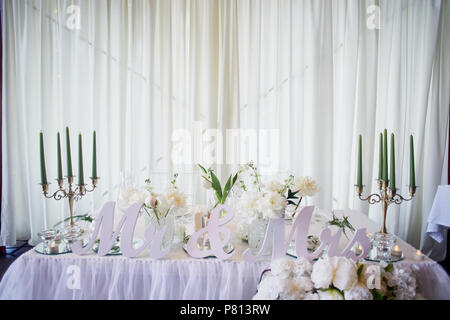 Guirlande de fleurs roses en forme de pin se bloque à partir de la table. Décoration de mariage, en art floral. Candélabres avec bougies verte.L'inscription M. et Mme. Enroulez la table avec chiffon Banque D'Images