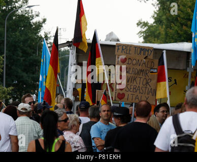 Kandel, Allemagne. 07Th Juillet, 2018. Les manifestants de droite écouter un discours au rassemblement, holding drapeaux allemands et un signe qui appelle à une libération de la militante d'extrême droite, Tommy Robinson et montre leur soutien à Donald Trump, Vladimir Poutine, Viktor Orban, Sebastian Kurz (Chancelier autrichien) et l'Italie. Autour de 200 personnes d'organisations d'extrême droite ont protesté pour la 10. heure de la ville de Kandel en Palatinat, contre les réfugiés, les étrangers et le gouvernement allemand. Ils ont appelé à davantage de sécurité d'Allemands et les femmes à partir de la prétendue augmentation de la violence par les réfugiés. Le lieu de la prote Banque D'Images