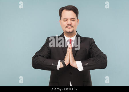 Au cours d'une pause de travail, il est préférable de faire du yoga pour mettre vos nerfs dans l'ordre. Piscine studio shot. isolé sur fond bleu clair. handsome businessman wi Banque D'Images