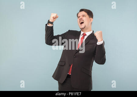 Businessman réjouissance a gagné le gros lot à la loterie. Piscine studio shot. isolé sur fond bleu clair. handsome businessman avec costume noir, rouge Banque D'Images
