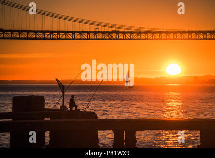 Silhouette d'un pêcheur sous le pont du 25 de Abril au coucher du soleil, Tage, Lisbonne, Portugal Banque D'Images