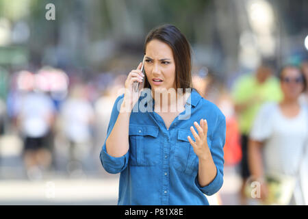 Vue avant, portrait d'une femme en colère réclamant sur le téléphone dans la rue Banque D'Images