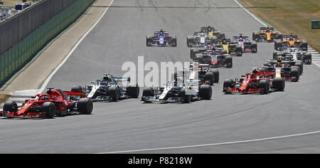 Ferrari Sebastian Vettel mène au premier virage suivi par Mercedes' Valtteri Bottas et Lewis Hamilton durant le Grand Prix de Grande-Bretagne 2018 à Silverstone, Circuit de Towcester. Banque D'Images