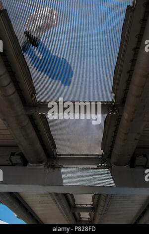 Les piétons marcher sur le pont du Millenium, vu d'en bas, à travers la grille transparente Banque D'Images