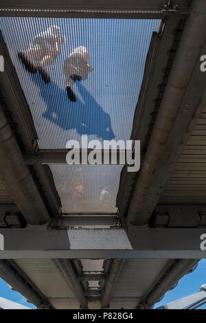 Les piétons marcher sur le pont du Millenium, vu d'en bas, à travers la grille transparente Banque D'Images