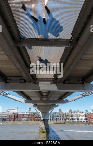 Les piétons marcher sur le pont du Millenium, vu d'en bas, à travers la grille transparente Banque D'Images