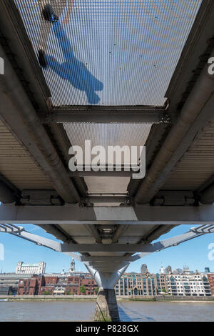 Les piétons marcher sur le pont du Millenium, vu d'en bas, à travers la grille transparente Banque D'Images