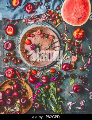 Divers petits fruits d'été et les fruits sur une table de cuisine de style rustique avec des fleurs et plaques, télévision, vue de dessus. Aliments biologiques locaux sains de saison et ea Banque D'Images