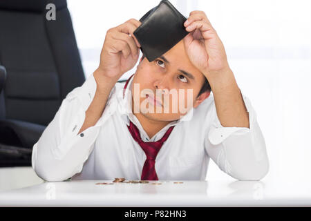 Un failli, a éclaté et l'homme est frustré avec des problèmes financiers avec coins gauche sur la table et un porte-monnaie vide. Banque D'Images