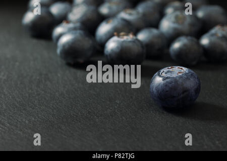 Groupe des bleuets canadiens frais est allongé sur une table en pierre sombre. Tout est sur un fond sombre. L'accent sur le premier plan, blueberry permanent Banque D'Images