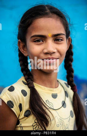 Jaipur - Rajasthan - Inde - 12 décembre 2017. Portrait d'une belle et souriante enfant indien avec ses cheveux rassemblés en tresses et un bleu backgroun Banque D'Images