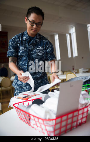 La NORFOLK (fév. 27, 2017) Hospital Corpsman 2e classe, Diosdado Valera de San Diego, et affectés à la porte-avions USS George Washington (CVN 73), plis fait don de t-shirts pendant un effort de volontaires à l'Ohef Sholom soupe populaire. Les marins affectés George Washington, le navire d'assaut amphibie USS Wasp LHD (1) et d'Assaut (ACU) 2 à partir de la plage de Marine Group (NBG) 2 se sont joints aux membres de l'Ohef Sholom dans la préparation des aliments et la distribution de marchandises données à ceux qui en ont besoin au cours de la soupe populaire mensuel du temple à Norfolk. Banque D'Images