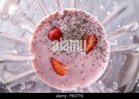 Préparation de lait de lait fouetté, fraises et chia graines dans un bol d'un mixeur, vue du dessus Banque D'Images