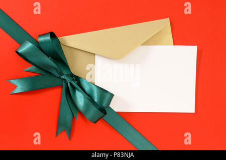 Carte de Noël ou d'anniversaire rouge sur fond de papier cadeau avec ruban vert avant. Banque D'Images