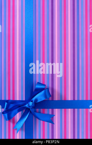 Blue Ribbon bow cadeau candy stripe sur fond de papier d'emballage, vertical Banque D'Images