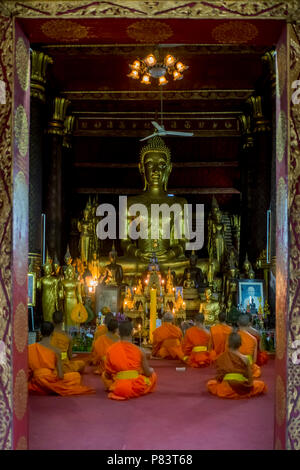 Les jeunes moines bouddhistes prient à l'intérieur d'un temple à Luang Prabang, Laos Banque D'Images