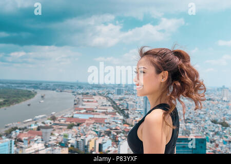 Smiling young woman in sportswear debout sur plus de ciel bleu sur le toit. Banque D'Images