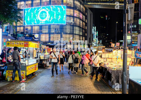 Des stands de nourriture de rue vendant des collations et des aliments le soir aux acheteurs dans le quartier commerçant de Myeongdong, Myeongdong, Séoul, Corée. Banque D'Images