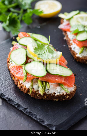 Sandwich avec du fromage à la crème, de saumon et de concombre sur fond ardoise, vue rapprochée, selective focus Banque D'Images