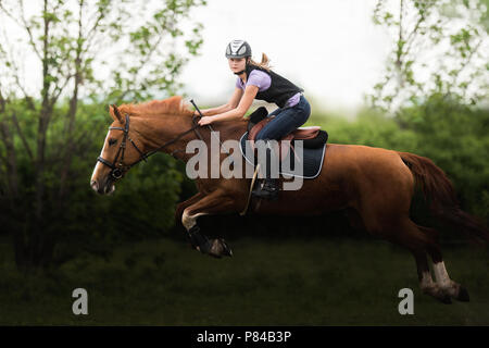 Young pretty girl riding a horse - sauts d'obstacle avec plus de temps au printemps Banque D'Images