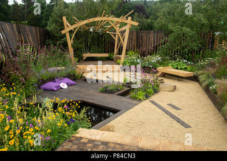 Des fleurs colorées, de bois, pergola et banc étang dans beau jardin spectacle primé, Le Grand extérieur - Chatsworth RHS Flower Show, England, UK. Banque D'Images