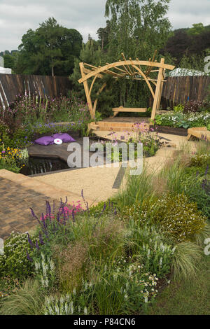 Des fleurs colorées, de bois, pergola et banc étang dans beau jardin spectacle primé, Le Grand extérieur - Chatsworth RHS Flower Show, England, UK. Banque D'Images