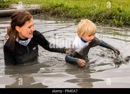 Biddinghuizen, Pays-Bas - le 23 juin 2018 : aider l'enfant pendant un mud run (mudraise) dans la boue et dans l'eau. Banque D'Images