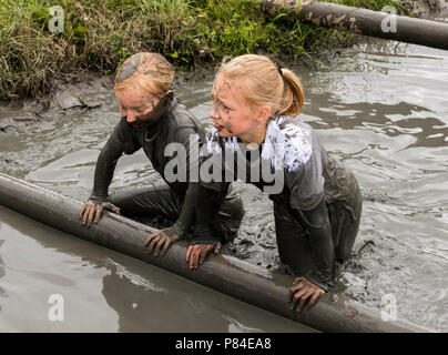 Biddinghuizen, Pays-Bas - le 23 juin 2018 : les enfants, les filles, au cours d'un mudrun (mudraise) dans la boue et dans l'eau escalade un tronc d'arbre. Banque D'Images