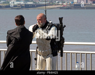 Un homme dans un costume de Storm Trooper prend le temps de sortir pour une cigarette tout en participant à un rassemblement sur la Guerre des étoiles Liverpool Waterfront. Banque D'Images