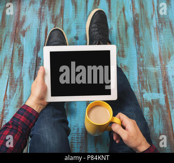 Haut voir l'image de man holding digital tablet with copy space et tasse de café assis à l'étage en bois Banque D'Images