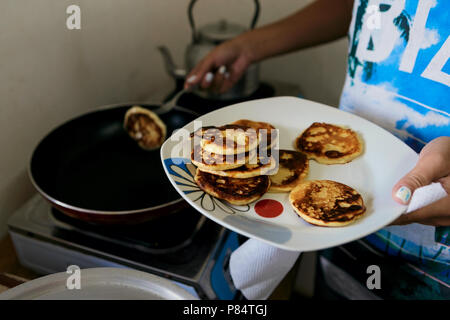 Jeune femme poêle crêpes pour le petit-déjeuner à la maison dans la cuisine Banque D'Images