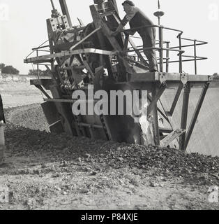 années 1950, historique, un homme portant une casquette en tissu debout sur la plate-forme d'une pelle mécanique haut sur le sommet d'une fosse en briques contrôlant la machine. Les célèbres œuvres de Stegartby Brick de la London Brick Co à Bedford, en Angleterre, abritent des fosses de briques géantes de l'enlèvement du mudrock connu sous le nom de « Oxford Clay », comme la compagnie britannique est devenue à cette époque, la plus grande entreprise de fabrication de briques dans le monde. Banque D'Images