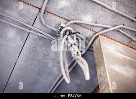 Boîtier de raccordement électrique avec tuyaux ondulés en plastique avec des câbles électriques dans le processus d'installation sur le plafond. Banque D'Images