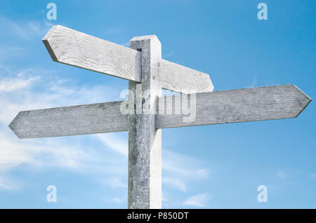 Old weathered wooden signpost against blue sky avec quatre choix signe pointant dans des directions différentes. Banque D'Images