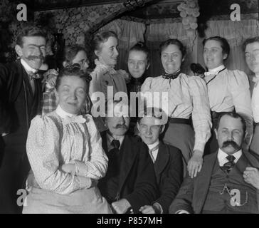 Un groupe de tournant du siècle adultes sourire et se réunir pour une photo de groupe, ca. 1900. Banque D'Images