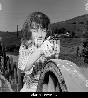 Une jeune femme s'occupe de six shooter dans une photo promotionnelle en Californie, ca. 1965. Banque D'Images